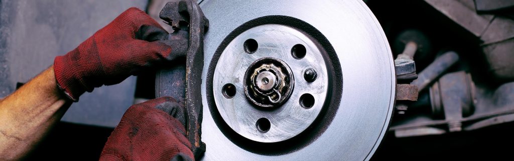 Mechanic wearing red work gloves servicing a car's disc brake assembly
