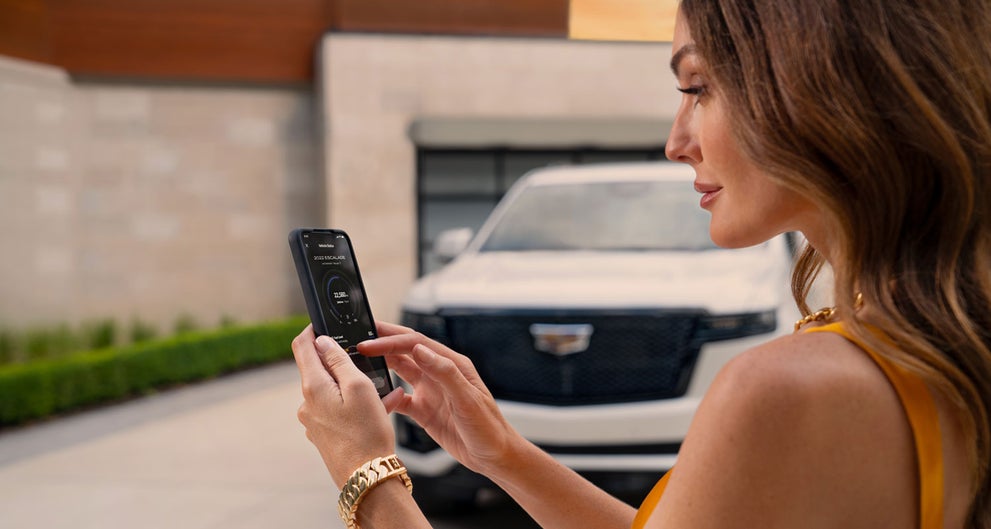 lady checking her mobile with a Cadillac vehicle background | Paradise Cadillac in Temecula CA